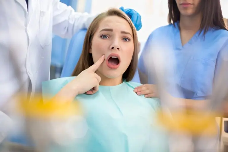 At Farr Orthodontics Georgetown, a woman sits in the dental chair, pointing to her mouth with concern as two dental professionals discuss treatment options for how to fix overbite in Georgetown, TX.