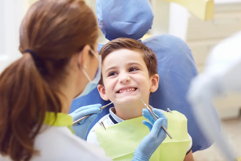 A boy smiles in a dental chair as a dentist examines his teeth at Farr Orthodontics Georgetown in Georgetown, TX for possible use orthodontic appliances.