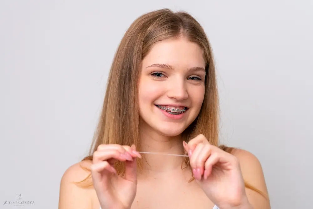 teenager russian girl with metal braces and floss isolated white background - How to Floss with Braces in Georgetown, TX. 