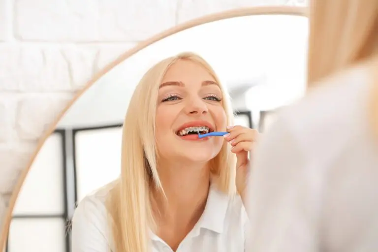 young woman metal braces toothbrush home - How to Floss with Braces in Georgetown, TX.