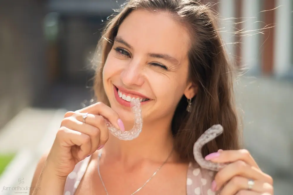 beautiful caucasian woman holding invisalign clear aligners for bite correction - Alternatives to Braces in Georgetown, TX 