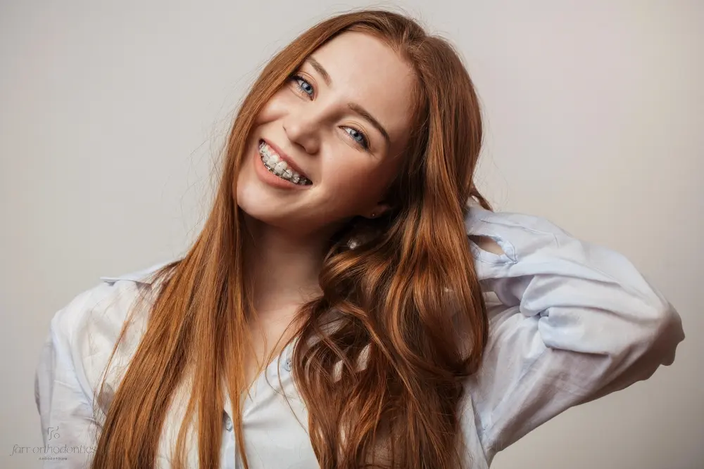 happy young red haired woman in clear braces smiling - Clear Braces vs. Metal Braces in Georgetown, TX 